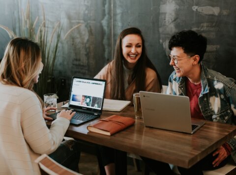 three people sitting in front of table laughing together